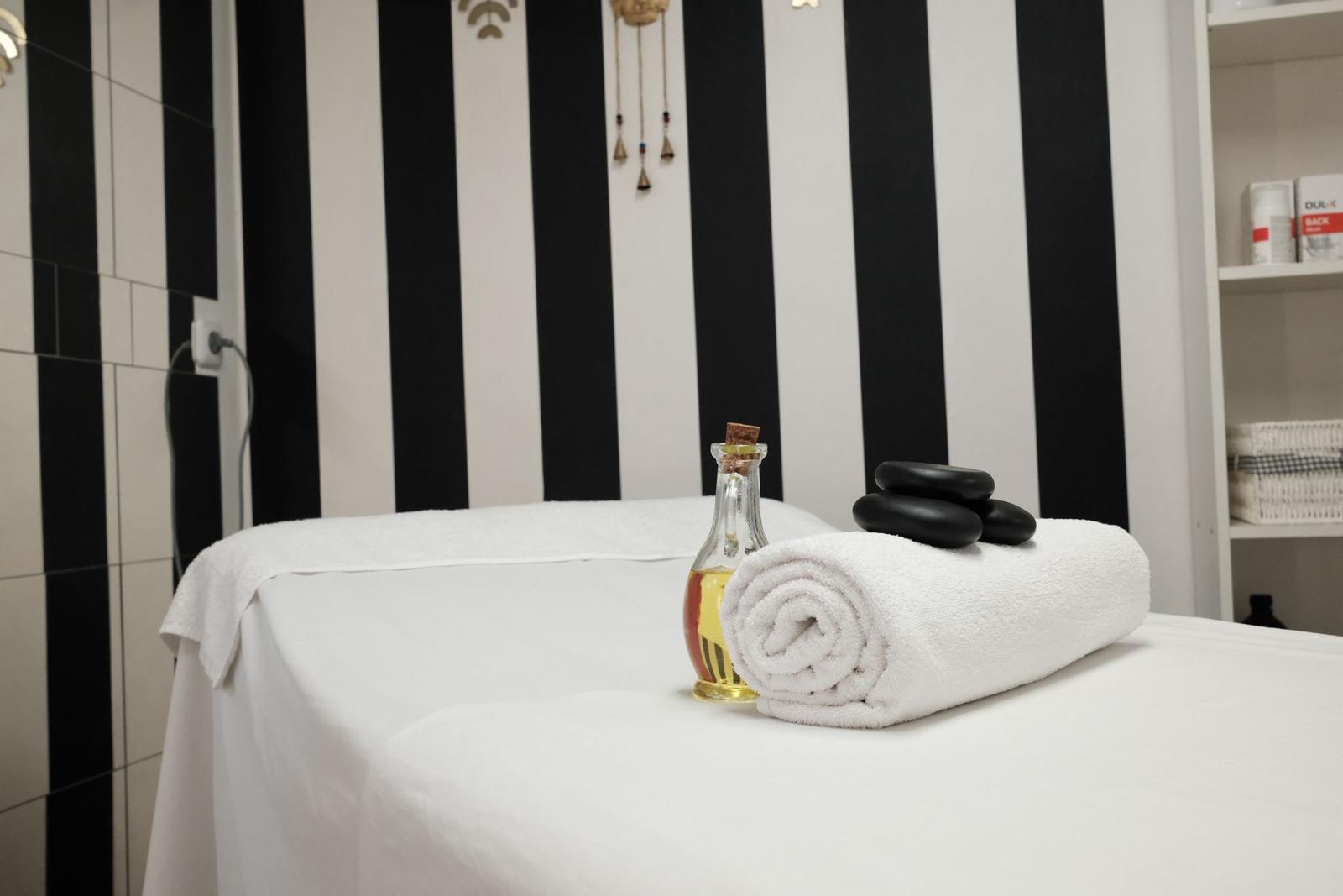 Massageliege mit Massageöl und warmen Hot-Stone-Steinen