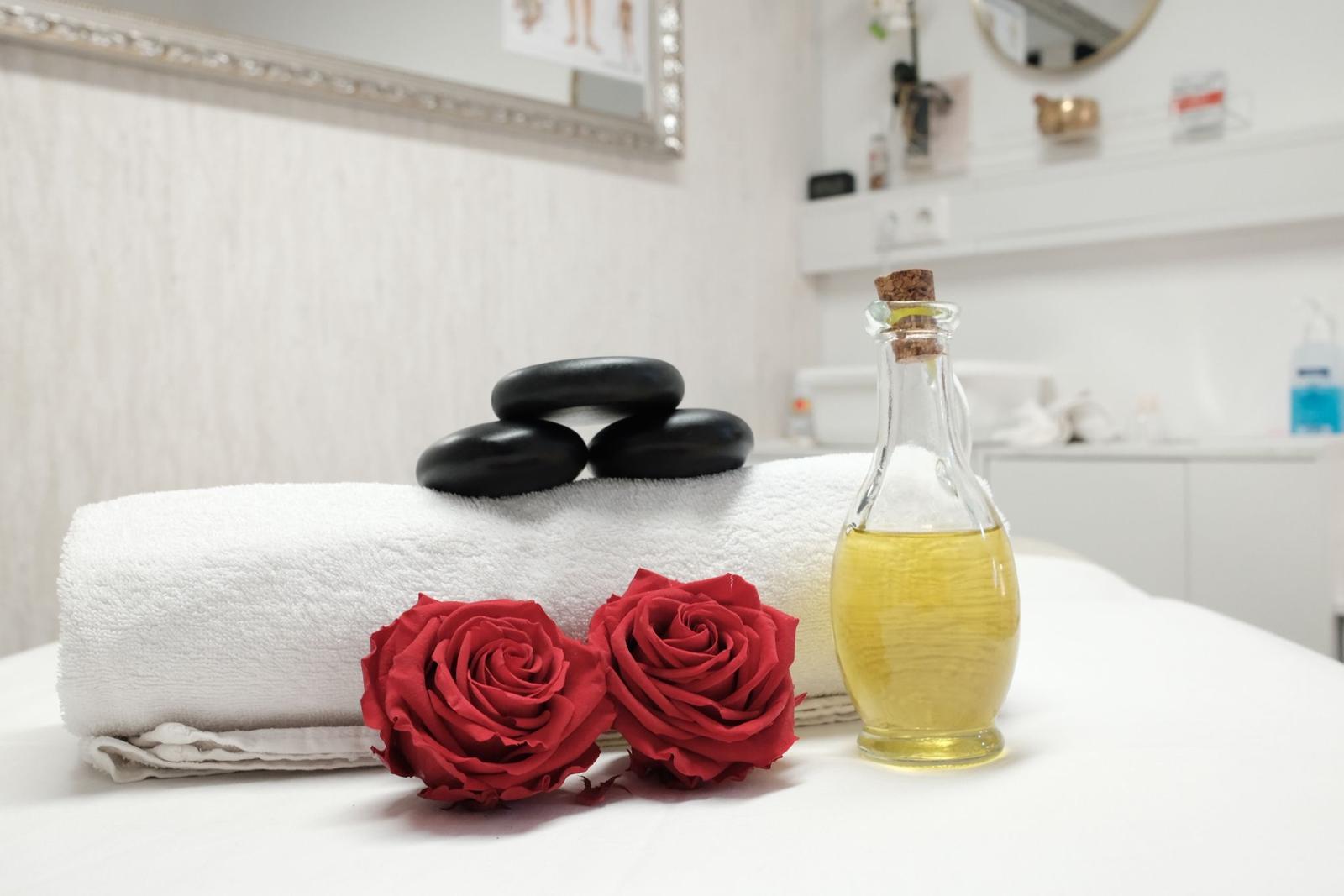 Frische Handtücher, Rosen und Massageöl auf der Behandlungsliege